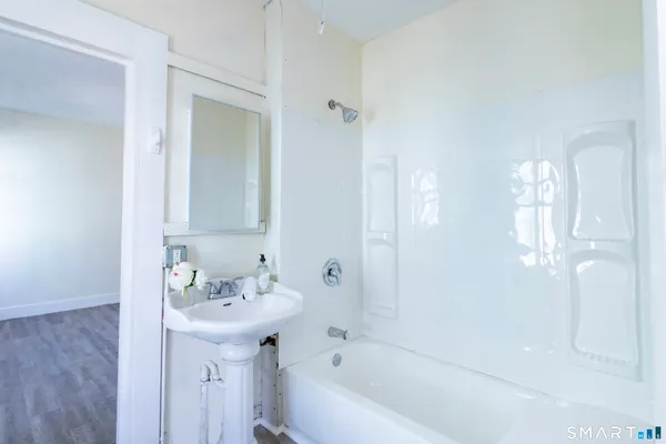 a bathroom with a bathtub shower sink and mirror