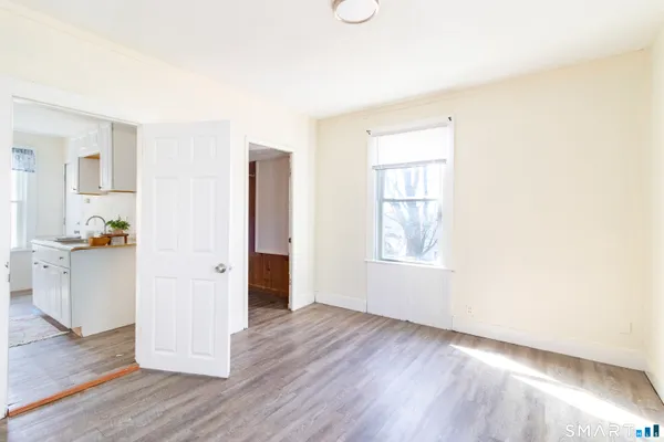 a view of empty room with wooden floor and fan