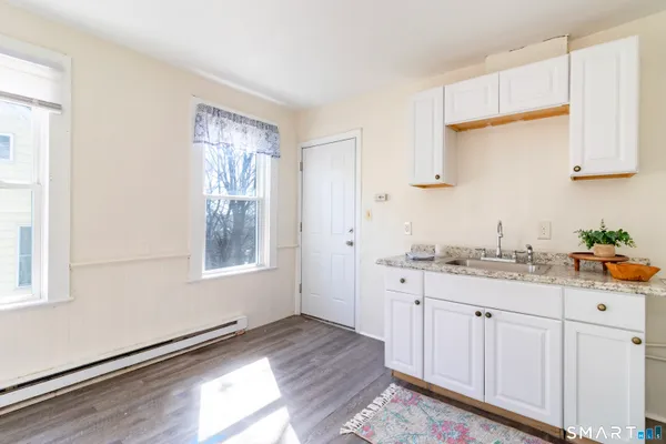 a kitchen with granite countertop white cabinets and wooden floor