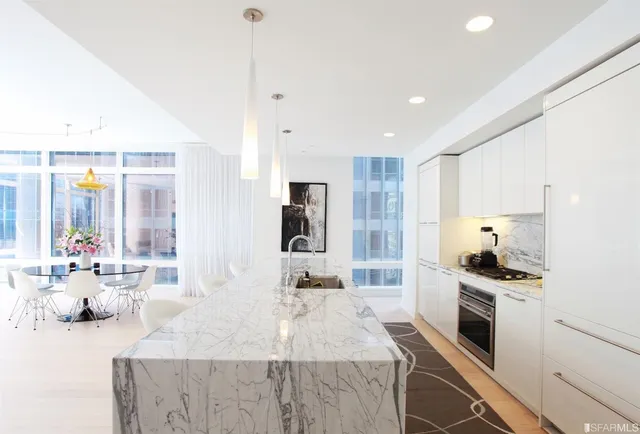 a large kitchen with kitchen island a large counter top stainless steel appliances and a window