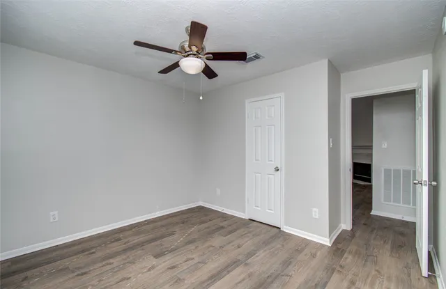 a view of a room with wooden floor and ceiling fan