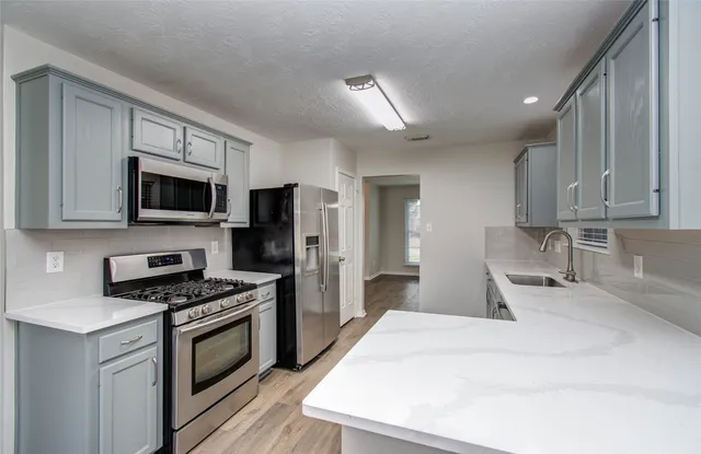 a kitchen with stainless steel appliances a stove microwave sink and refrigerator