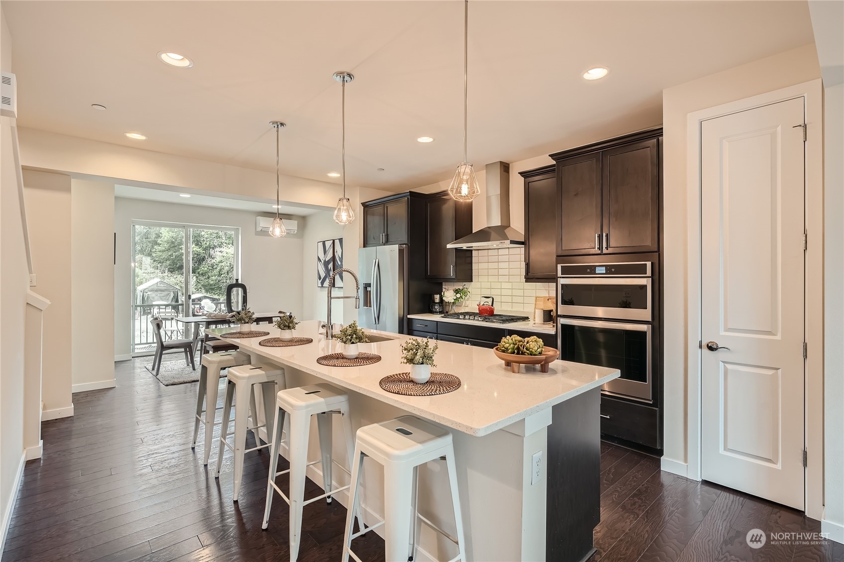 603 237th Street Southeast, Unit B Bothell, WA 98021 - Photo 8 of 27 a kitchen with stainless steel appliances kitchen island granite countertop a refrigerator a stove a sink a dining table and chairs with wooden floor