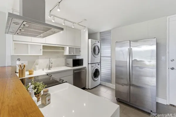 a kitchen with stainless steel appliances granite countertop a refrigerator a sink and white cabinets