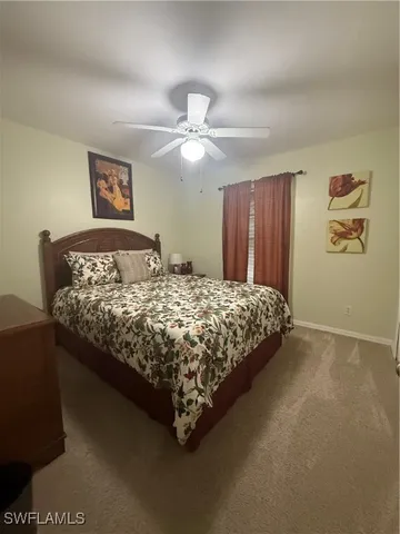 a bedroom with a bed painting on wall and two windows