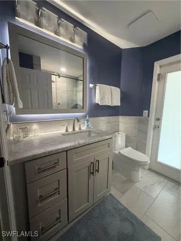 a bathroom with a granite countertop toilet sink and mirror