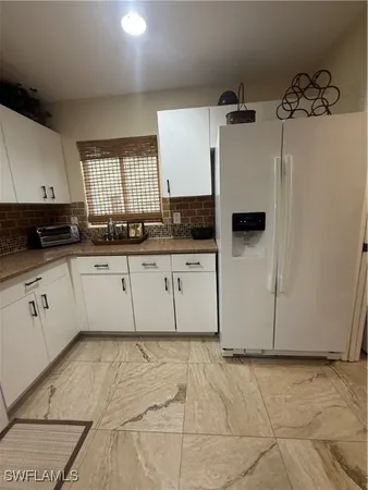 a kitchen with granite countertop a sink a stove a refrigerator and cabinets