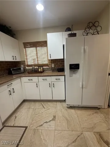 a kitchen with granite countertop a sink a stove a refrigerator and cabinets