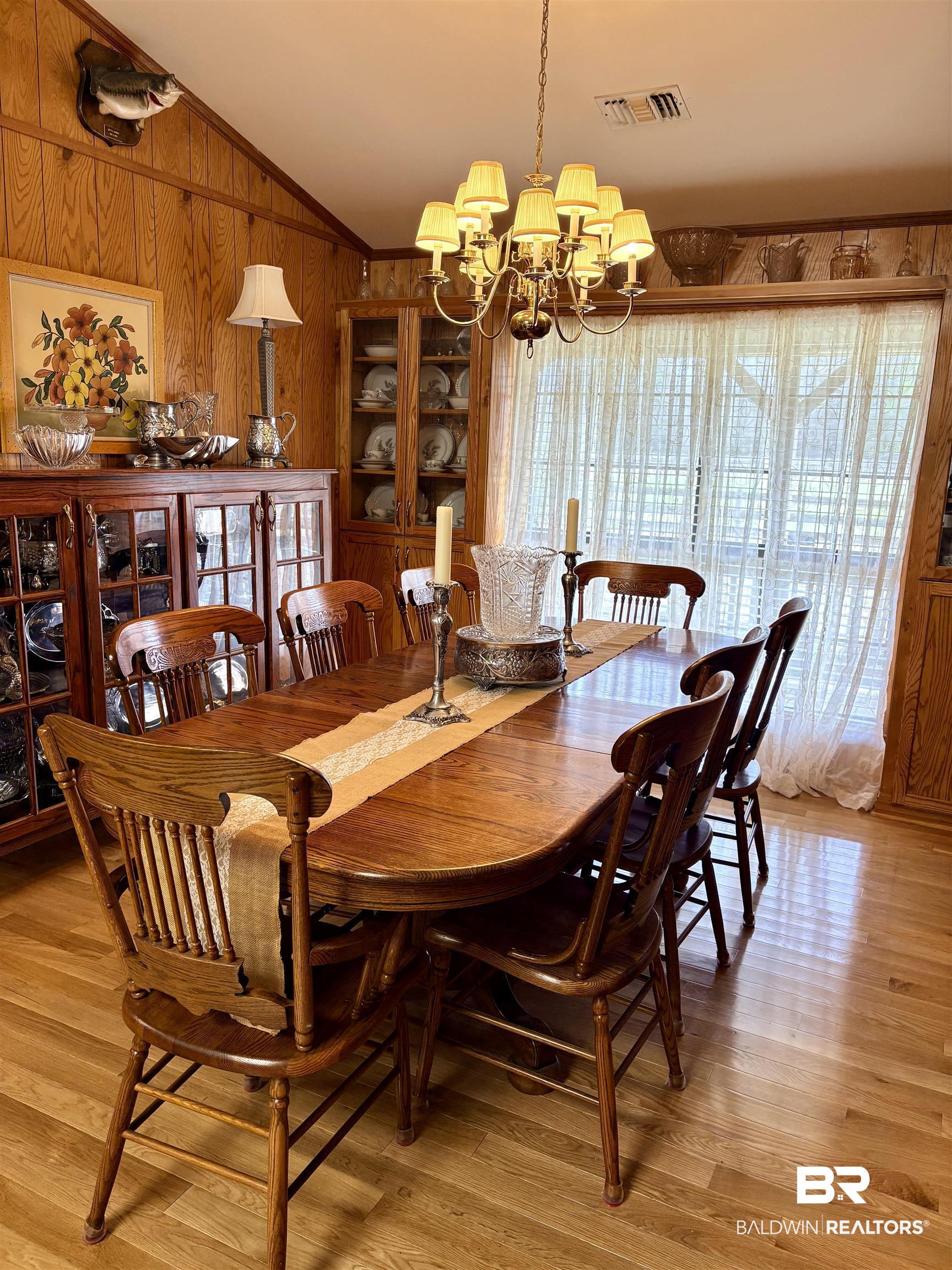 44 Ridge Road Castleberry, AL 36432 - Photo 14 of 33 Dining area with suspended lighting, lofted ceiling, light wood-style floors, wooden walls, and crown molding