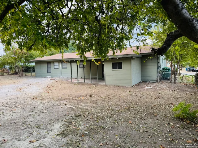 a view of a house with a yard plants and large tree