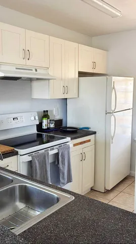 a kitchen with granite countertop a sink and a refrigerator