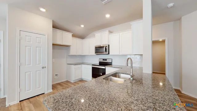 a kitchen with white cabinets and stainless steel appliances