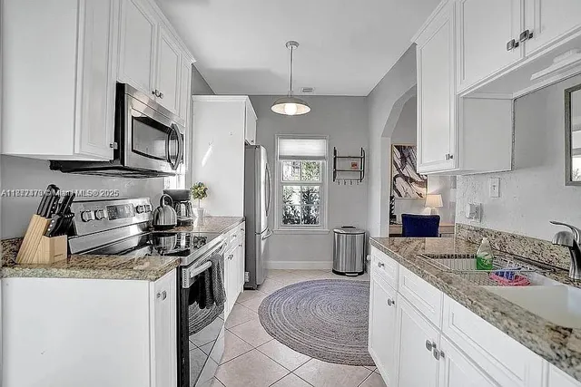 a kitchen with stainless steel appliances granite countertop a sink stove microwave and refrigerator