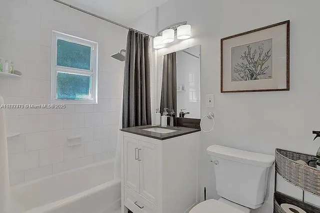 a bathroom with a granite countertop sink a toilet a mirror and a bathtub