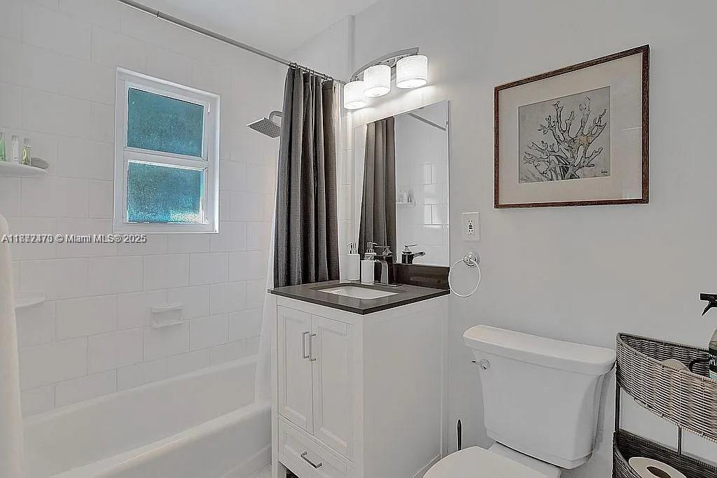8900 Harding Avenue Surfside, FL 33154 - Photo 16 of 25 a bathroom with a granite countertop sink a toilet a mirror and a bathtub