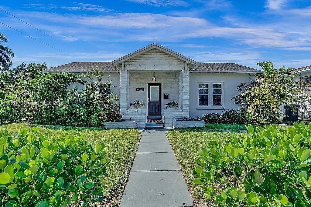 8900 Harding Avenue Surfside, FL 33154 - Photo 3 of 25 a view of a house with a small yard plants and large tree