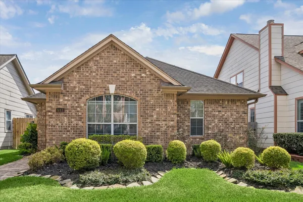 a view of a brick house with a yard and plants