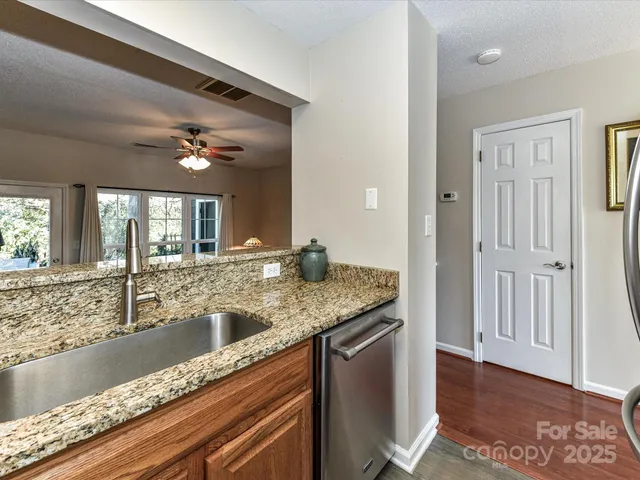 a view with granite countertop a sink and a large mirror with wooden floor