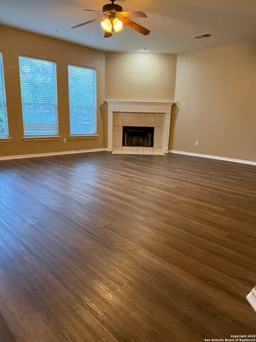 an empty room with wooden floor fireplace and windows