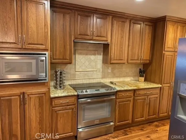 a kitchen with stainless steel appliances granite countertop a stove microwave and cabinets
