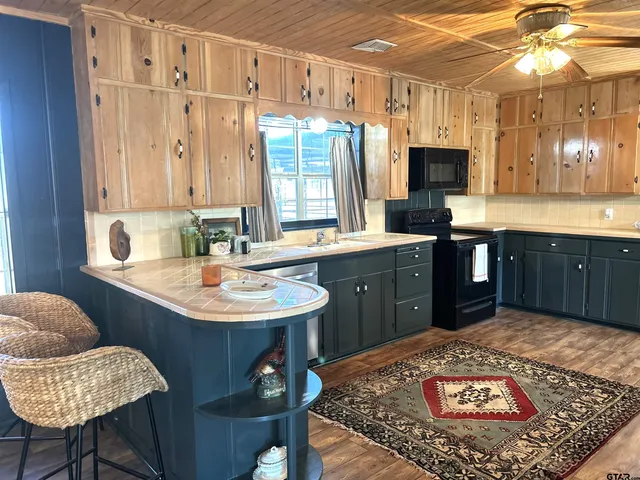 a kitchen with stainless steel appliances granite countertop a sink dishwasher and a stove with wooden floor