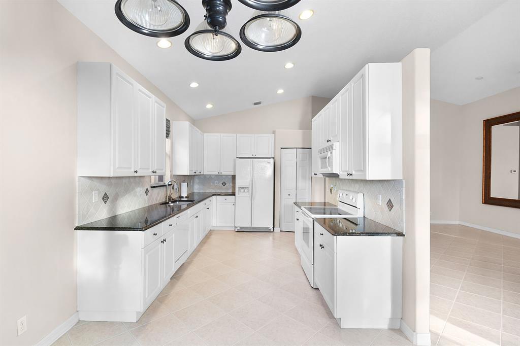 7084 Southeast Cricket Court Stuart, FL 34997 - Photo 11 of 51 a large white kitchen with a large window and stainless steel appliances