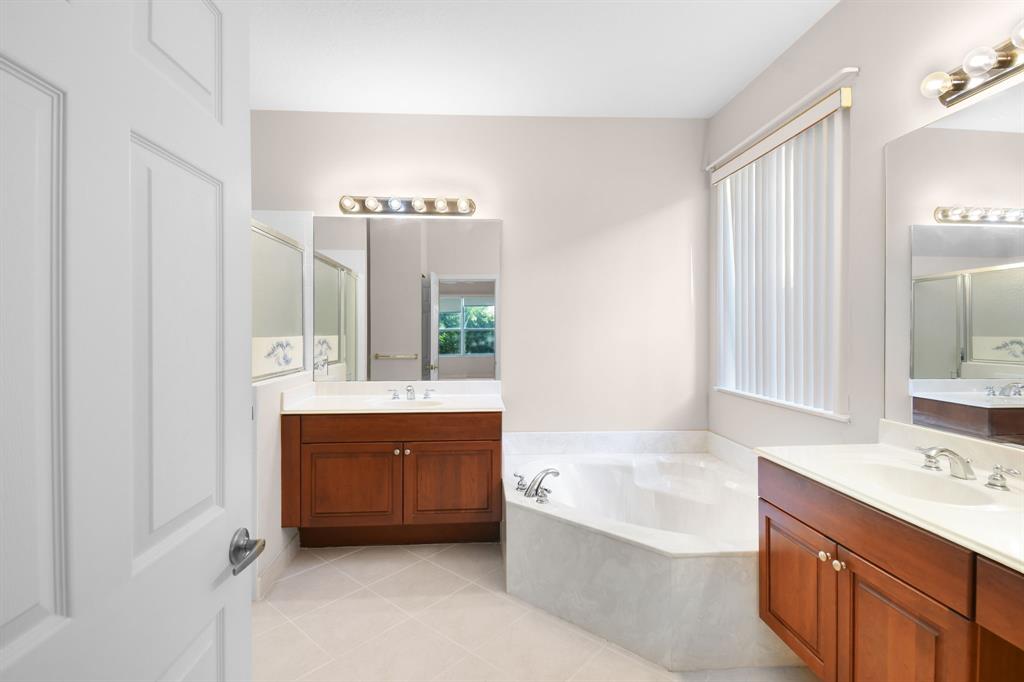 7084 Southeast Cricket Court Stuart, FL 34997 - Photo 19 of 51 a bathroom with a tub double vanity sink and mirror