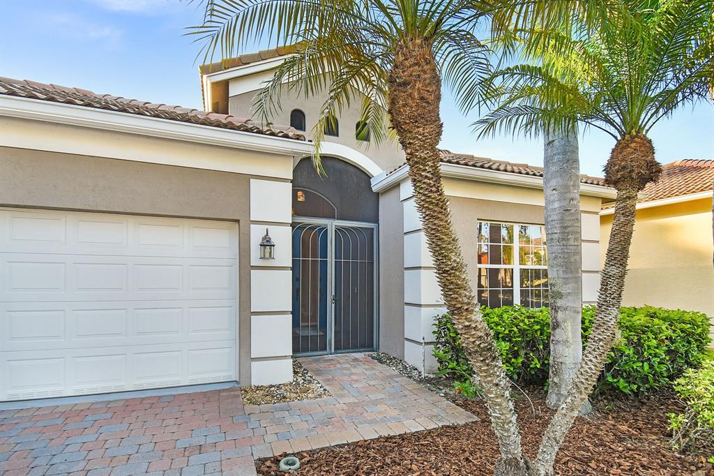 7084 Southeast Cricket Court Stuart, FL 34997 - Photo 2 of 51 a view of a white house with a large window and potted plants