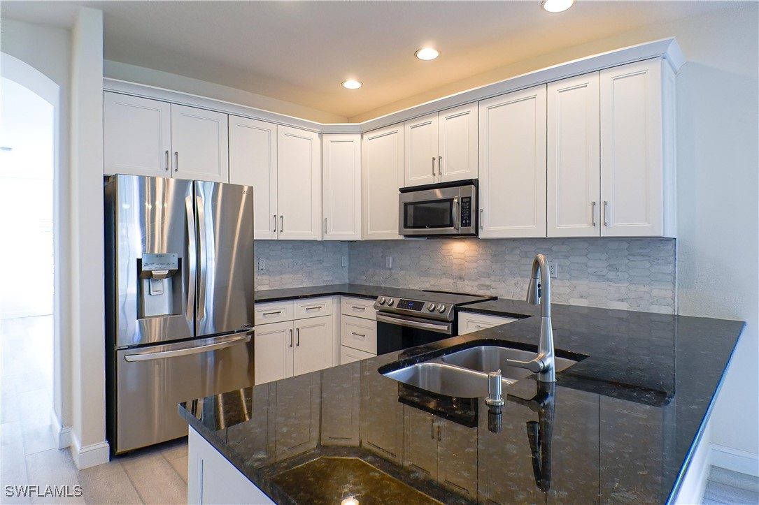 8876 Falcon Pointe Loop Fort Myers, FL 33912 - Photo 9 of 31 a kitchen with stainless steel appliances granite countertop a refrigerator a stove and a sink with wooden floor