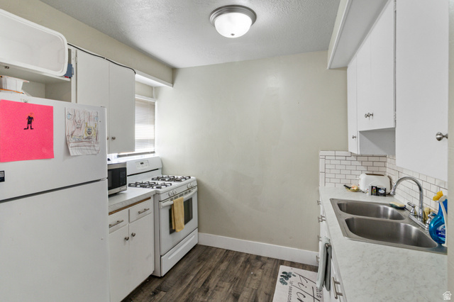 386 North 500 East Provo, UT 84606 - Photo 11 of 24 Kitchen with white cabinetry, white appliances, light countertops, a textured ceiling, and dark wood-type flooring
