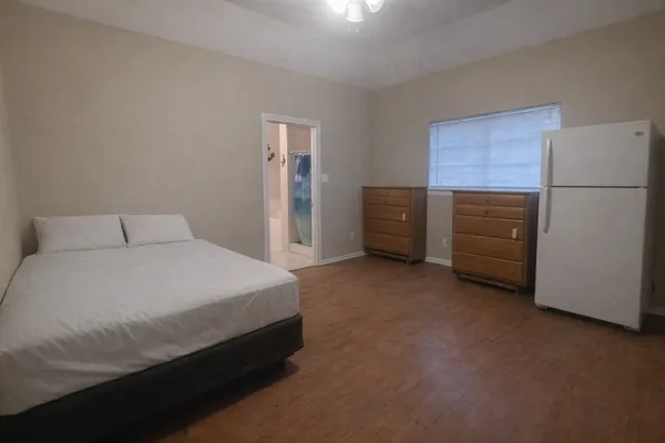 a bedroom with a bed and a refrigerator