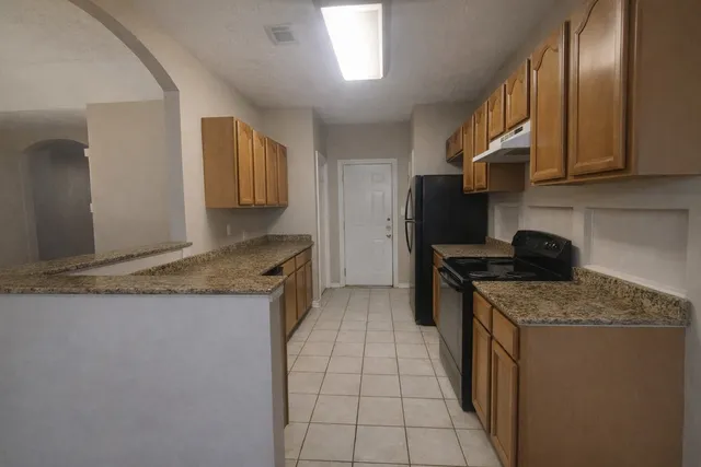 a kitchen with granite countertop a sink a stove oven and cabinets