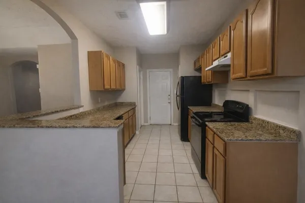 a kitchen with granite countertop a sink a stove oven and cabinets