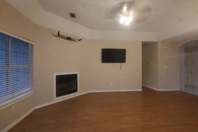 a view of an empty room with a fireplace and a window