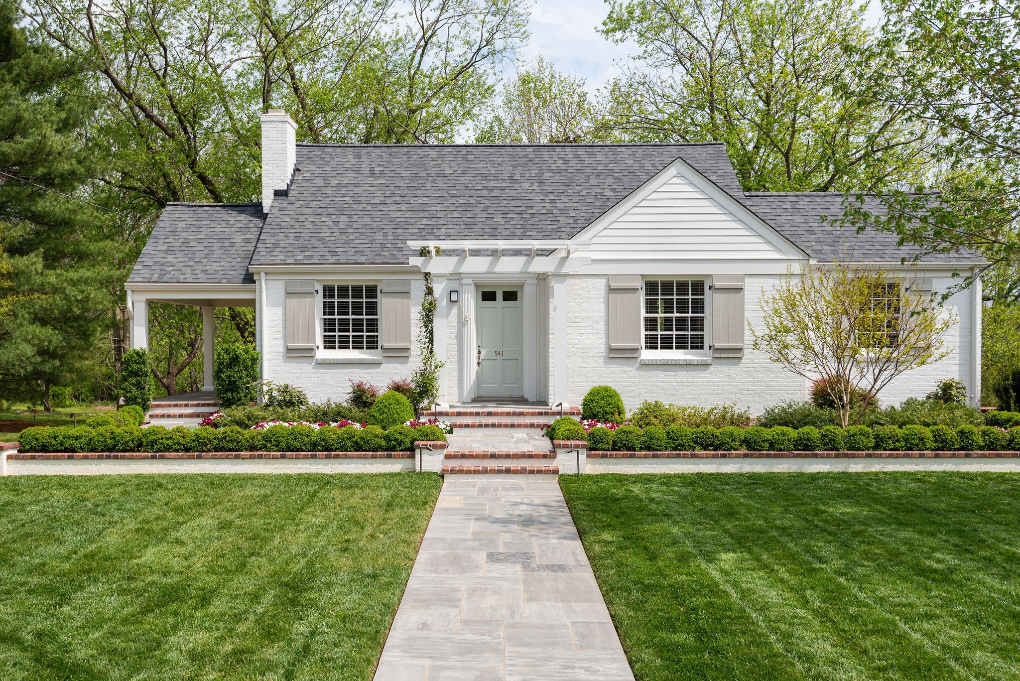a front view of a house with a yard and potted plants