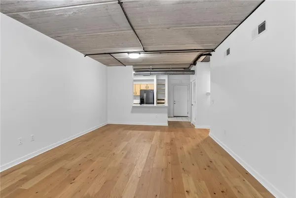 a view of a big room with wooden floor and windows