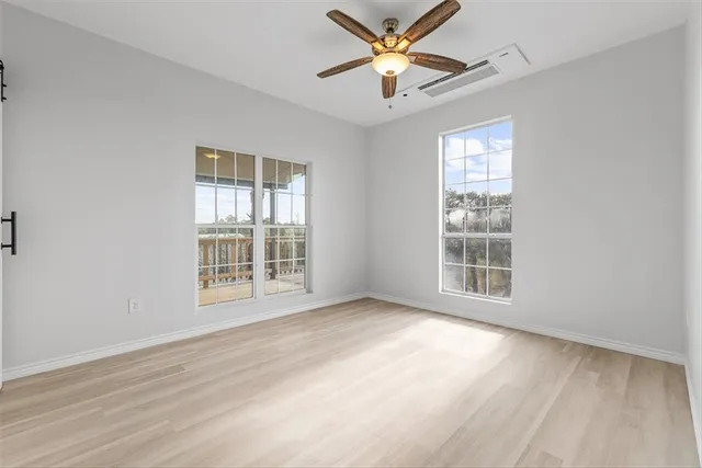 a view of an empty room with a window and wooden floor