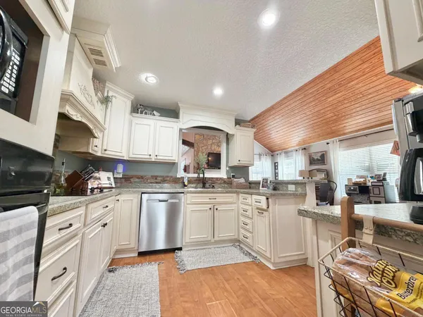 a kitchen with stainless steel appliances granite countertop a stove top oven a sink a dining table and chairs