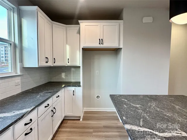 a kitchen with granite countertop white cabinets and sink