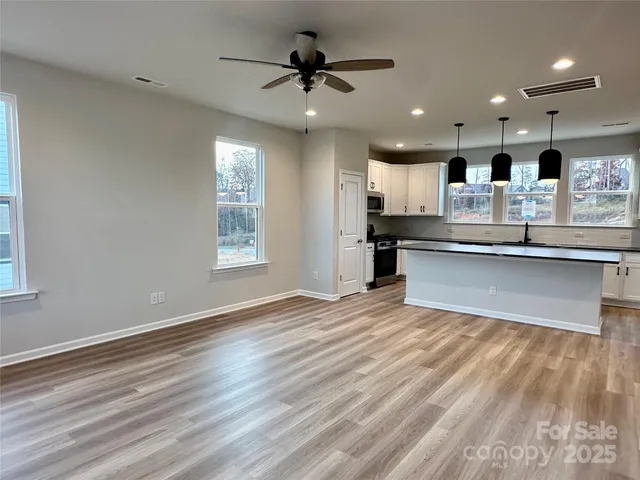 a view of kitchen with kitchen island wooden floors and stainless steel appliances