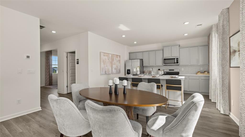 182 Aster Avenue Locust Grove, GA 30248 - Photo 17 of 48 a kitchen with kitchen island a dining table chairs stainless steel appliances and cabinets