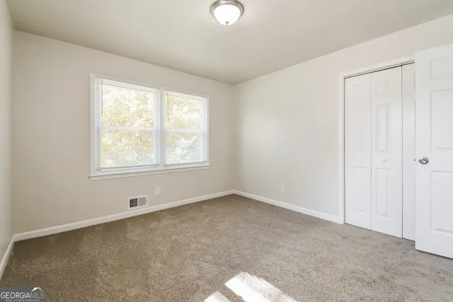 an empty room with chandelier fan and windows