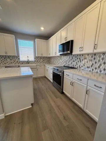 a kitchen with stainless steel appliances granite countertop a stove a sink and a microwave