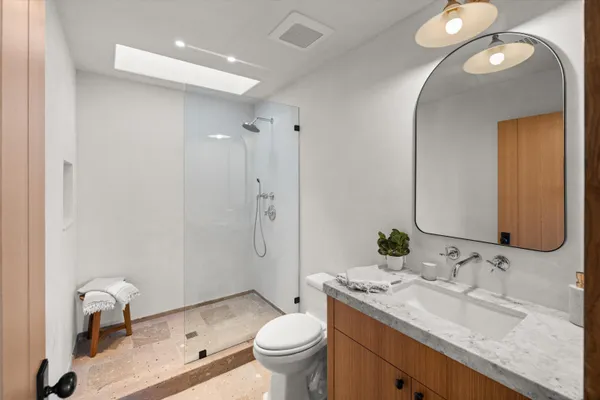 a bathroom with a granite countertop toilet a sink and a mirror