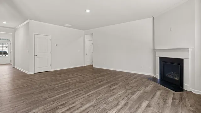 a view of a kitchen and an empty room with wooden floor and a window