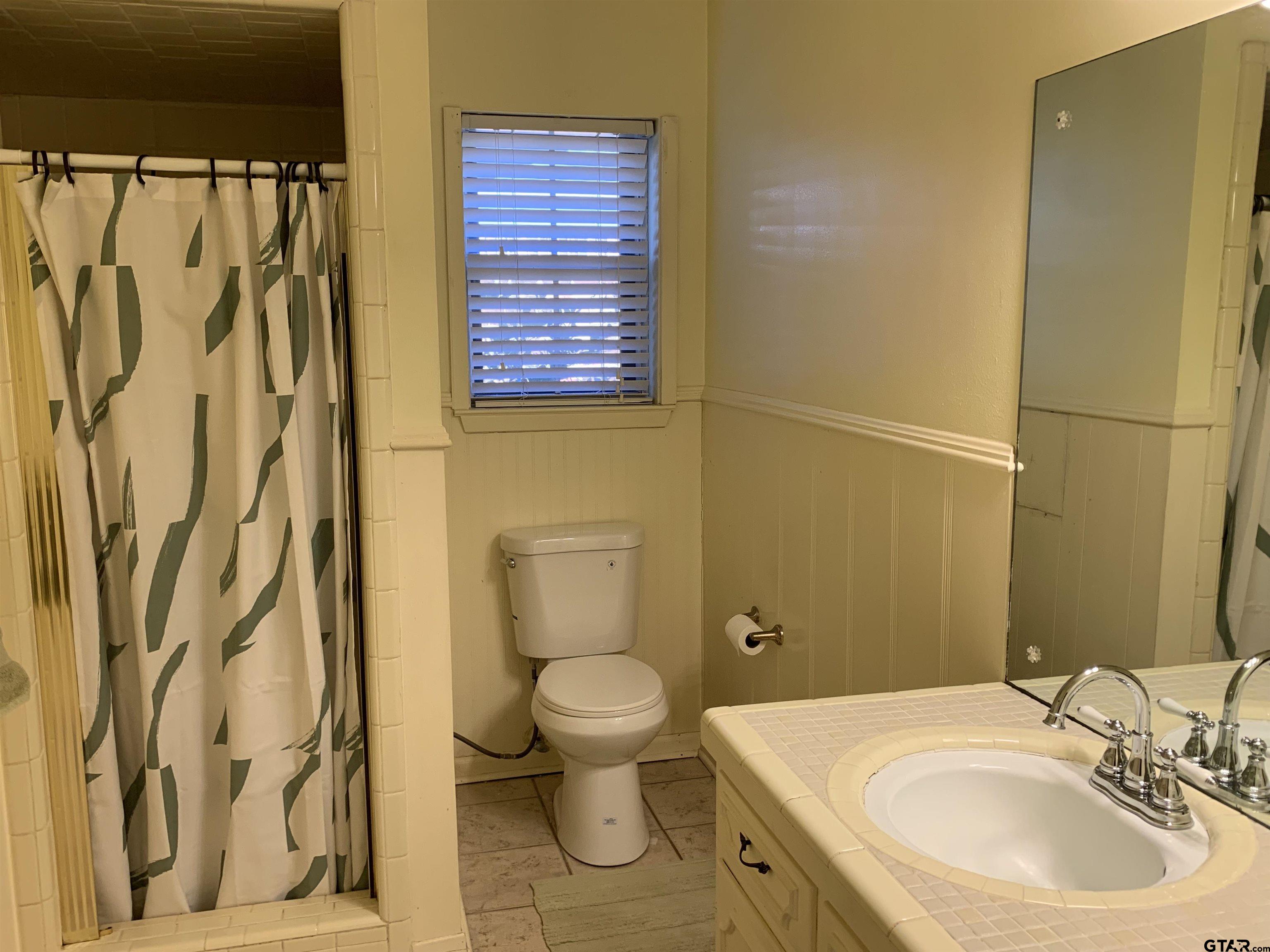 800 Neches Drive Tyler, TX 75702 - Photo 21 of 26 a bathroom with a sink a toilet and shower curtain