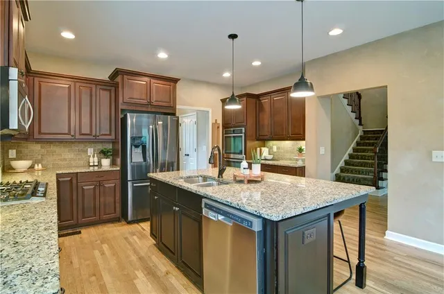 a kitchen with granite countertop wood cabinets stainless steel appliances and a sink
