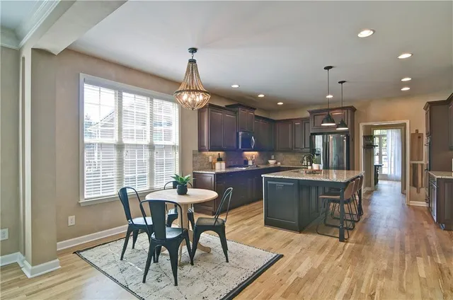 a kitchen with granite countertop a table chairs in it and wooden floors