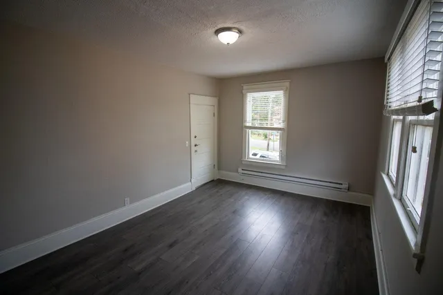 an empty room with wooden floor and windows
