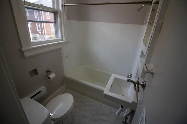 a bathroom with a granite countertop bathtub sink window vanity and toilet
